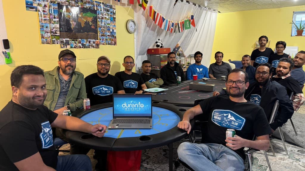 Duronto Hikers members gathered together in matching club shirts around a table with the Duronto Hikers logo on a laptop