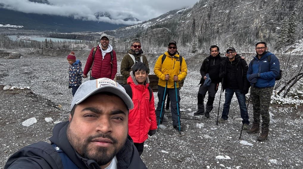 Duronto Hikers group selfie on a rocky mountain trail with snowy peaks and valley in the background