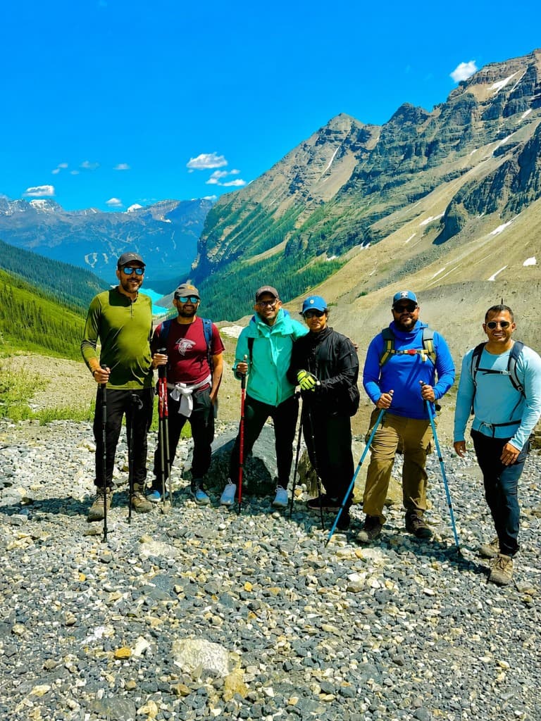 Duronto Hikers group posing on a mountain trail with a turquoise alpine lake and peaks in the background